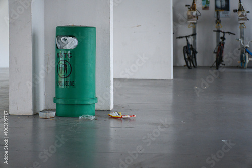 Overflowed litter bin with rubbish thrown outside the bin on the ground.