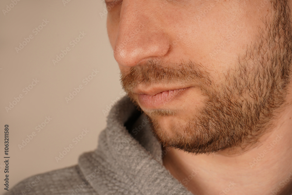 Obraz premium Portrait of bearded man's face in hoodie. Male expressing his masculinity and charisma. Handsome face. Man's beauty. Close up of young unshaved guy isolated over neutral background.