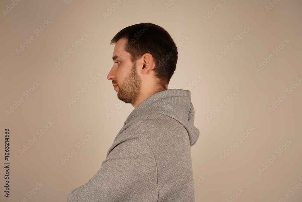 Side view. Handsome male. Neutral background. Man in casual clothes. Young man standing in front of camera. Guy looking at side. Crossed hands. Side view. Handsome male. Neutral background. Man in casual clothes. Young man standing in front of camera. Guy looking at side. Crossed hands.