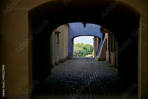 Dark archway through an old house with a view of the greenery in summer in the historic centre of the Polish capital Warsaw, 
Warszawa, Poland photo