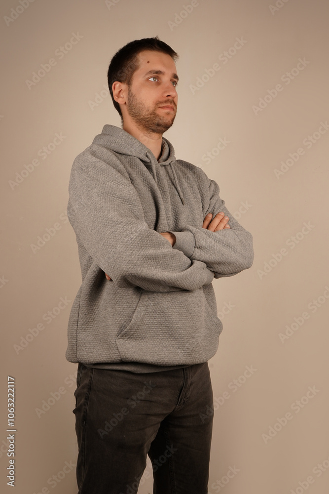 Person looking at camera having crossed hands. Handsome man. Young guy standing in front of camera with neutral background. Man in casual clothes with side view. Person looking at camera having crossed hands. Handsome man. Young guy standing in front of camera with neutral background. Man in casual clothes with side view.