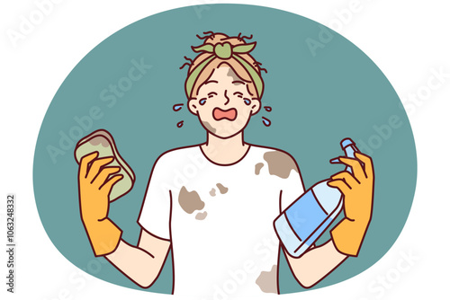 Woman housewife in dirty clothes is crying because of large amount housework and lack of rest. Girl housewife with tears in eyes holds sponge and spray bottle for cleaning in apartment