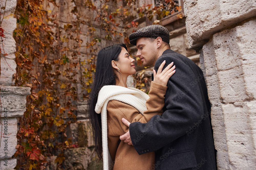 A couple enjoys a tender moment in warm autumn clothing amidst colorful fall foliage. A couple enjoys a tender moment in warm autumn clothing amidst colorful fall foliage.