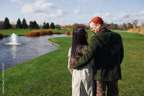 A couple enjoys a warm autumn day, wrapped in each others embrace near a tranquil lake. photo