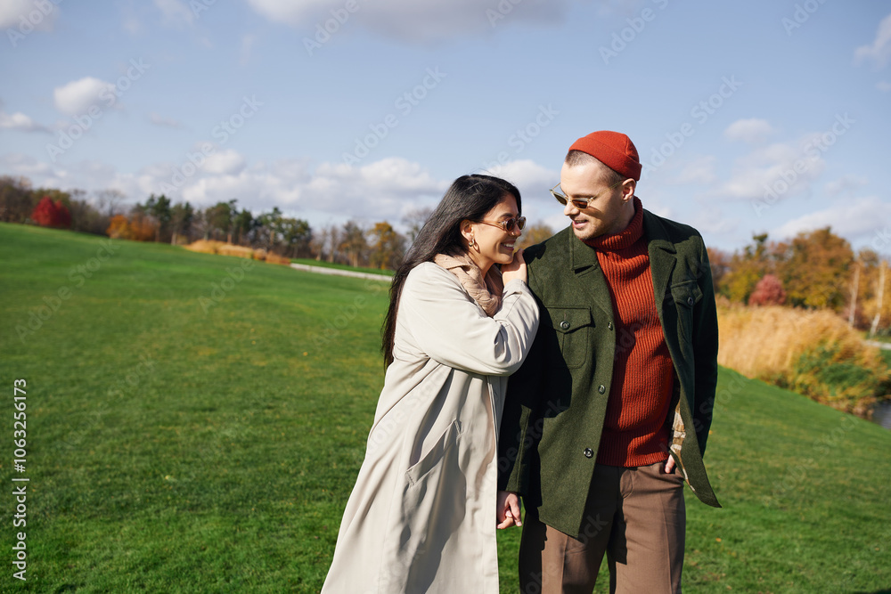 A couple shares laughter while walking through a picturesque park on a bright autumn day. A couple shares laughter while walking through a picturesque park on a bright autumn day.