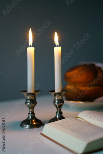 Traditional challah bread with wine and glowing candles on dark background. Shabbat Shalom