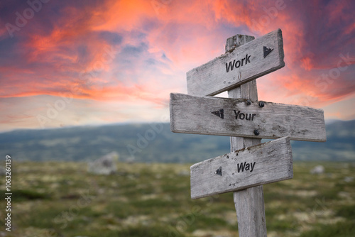 work your way text quote written on wooden signpost outdoors in nature. Red dramatic skies in the background