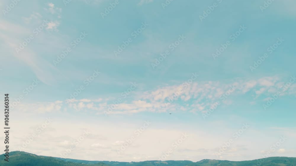 A lone eagle bird soars high above a mountainous landscape under a bright open sky. A lone eagle bird soars high above a mountainous landscape under a bright open sky.