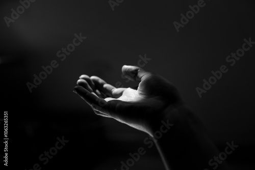 Cuadro en lienzo Main tendue vers la lumière, clair obscur sur fond noir.