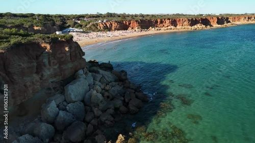 Drone flight over Cala del Aceite in Cadiz, Andalucia, Spain. People enjoying a summer day on a beach with crystal clear water. Mediterranean coast