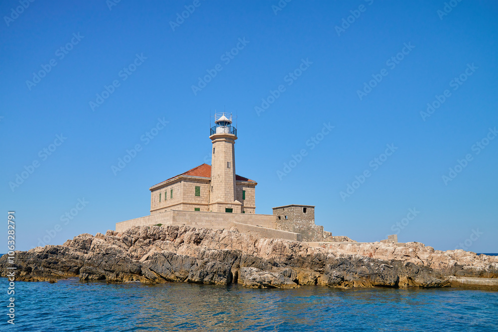 Sea landscape with lighthouse on tall rocky island in sea on sunny day Sea landscape with lighthouse on tall rocky island in sea on sunny day