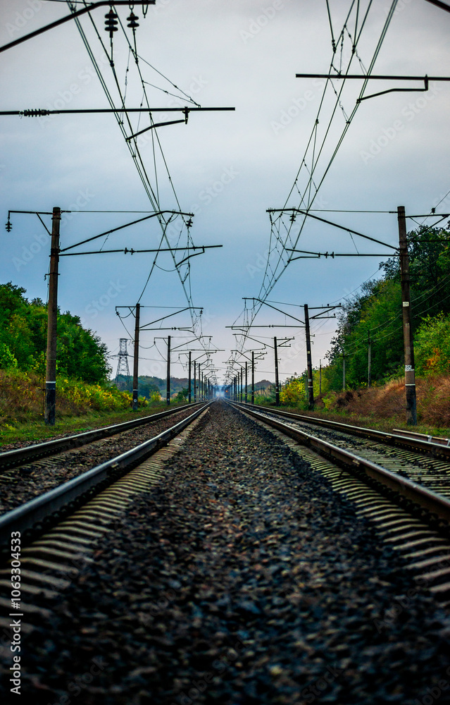 Railway road at autumn evening with autumn colors.Railroad near the forest with powerlines over the trees.Clouds in the sky,photography in the rainy weather .Landscape photo with train on the rails Railway road at autumn evening with autumn colors.Railroad near the forest with powerlines over the trees.Clouds in the sky,photography in the rainy weather .Landscape photo with train on the rails