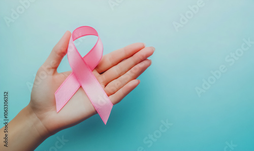 A pink ribbon rests on a hand’s palm against a soft blue background, symbolizing breast cancer awareness. Perfect for medical campaigns, social media, and charity promotions.