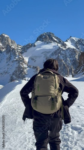 Skiers climbing a snowy slope in the mountains of Almaty, Kazakhstan, with majestic peaks in the background under a bright blue sky. A scene of winter adventure and alpine exploration.