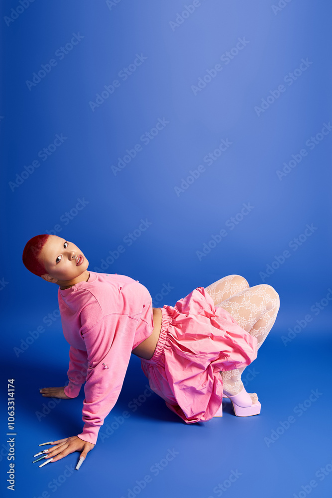 A confident young woman with short pink hair models her striking outfit in a bright studio setting. A confident young woman with short pink hair models her striking outfit in a bright studio setting.