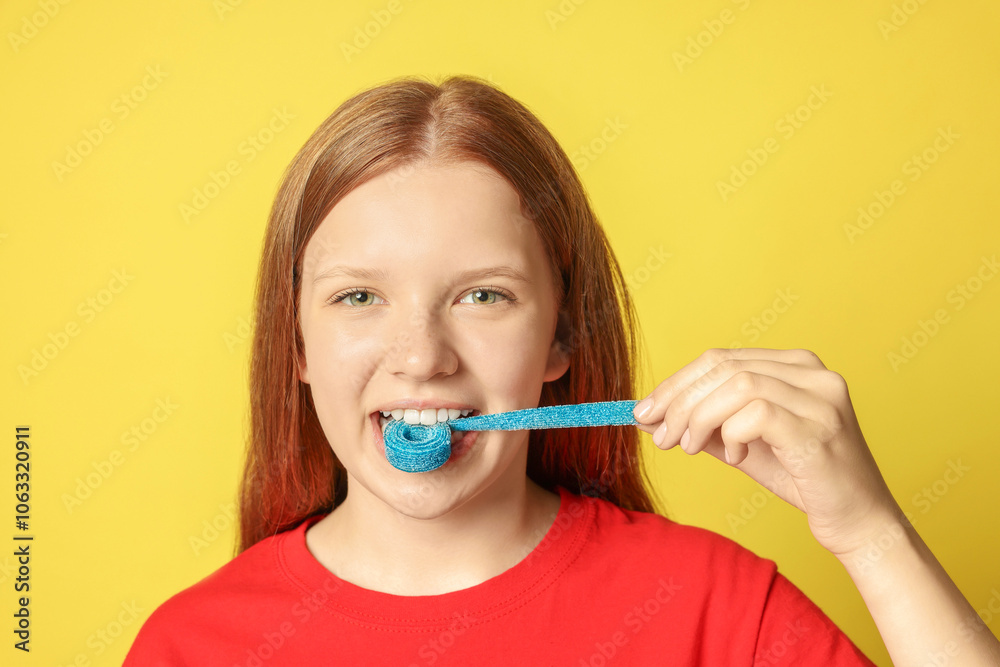Teenage girl eating tasty gummy candy on yellow background Teenage girl eating tasty gummy candy on yellow background