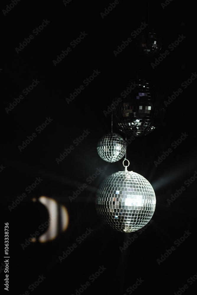 Obraz premium three disco balls suspended against a black space, reflecting the light and creating a retro party atmosphere. party poster in the style of the 80s or for visual advertising of events with an atmosphe