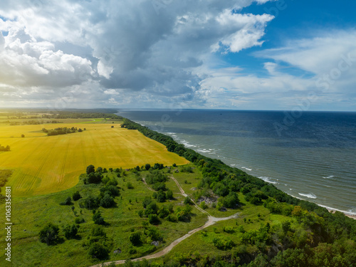 Aerial view of calm and wild Saka beach with a clear blue water on a cloudy summer day. Beautiful yellow and green fields and countryside road. Saka, Ida Viru county, Estonia.  photo