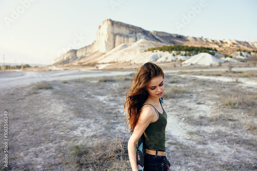 Majestic mountain backdrop as woman stands in serene field under clear blue sky photo