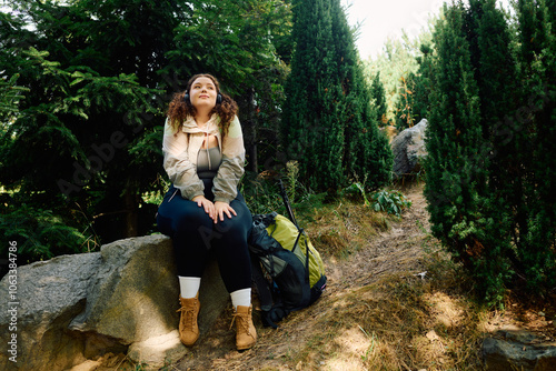 A joyful plus size woman relaxes in a picturesque forest, surrounded by natures beauty.