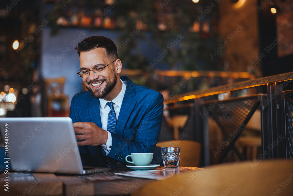 Smiling Businessman Working on Laptop in Modern Cafe Smiling Businessman Working on Laptop in Modern Cafe