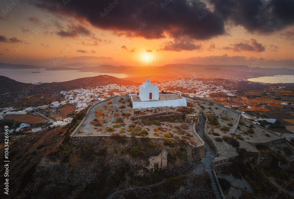 Stunning view from Milos Island's peak, Greece: a white church overlooks the vast Aegean Sea, surrounded by rolling hills and the iconic Cycladic landscape.