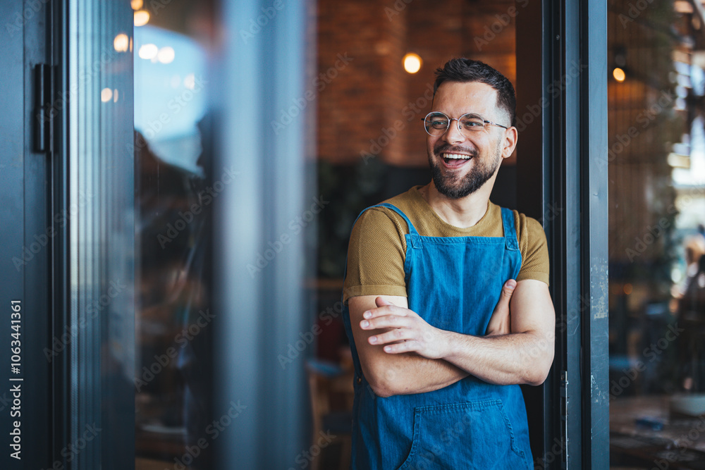 Smiling Barista in Denim Apron Standing at Cafe Entrance Smiling Barista in Denim Apron Standing at Cafe Entrance