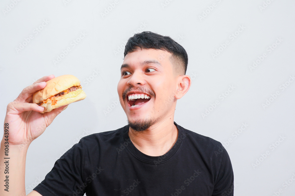 portrait of a young asian man is eating hamburger, isolated on white background. Fast food advertising portrait of a young asian man is eating hamburger, isolated on white background. Fast food advertising