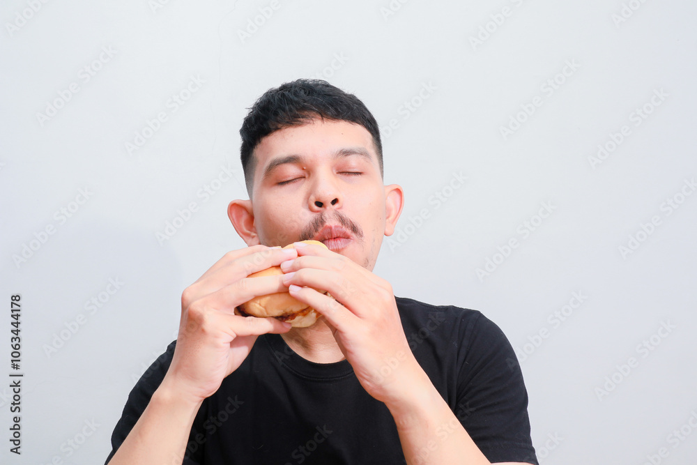 portrait of a young asian man is eating hamburger, isolated on white background. Fast food advertising portrait of a young asian man is eating hamburger, isolated on white background. Fast food advertising