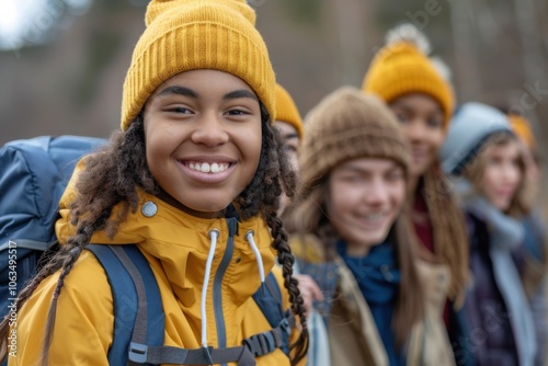 A group of young friends are hiking in the countryside, dressed in warm clothing and bright, colorful hats, enjoying a cheerful outdoor adventure.