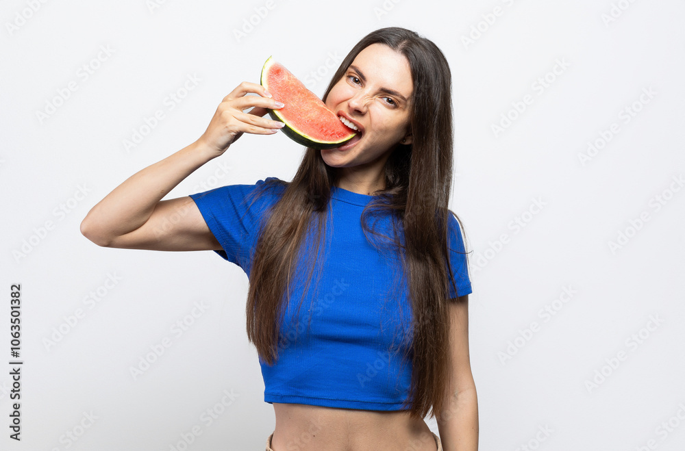Beautiful brunette with a blue top biting into a slice of watermelon. On white background. Beautiful brunette with a blue top biting into a slice of watermelon. On white background.