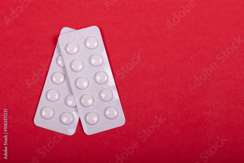 White Pharmaceutical Pills in Blister Packs Arranged on Vibrant Red Background - Medication, Healthcare, and Medical Treatment Concept photo