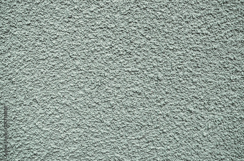 A grey wall with a rough texture. The wall is covered in small bumps and ridges, giving it a somewhat uneven appearance. The texture of the wall is not smooth, but rather rough and bumpy.