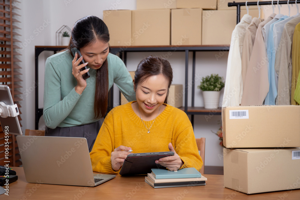 Two young asian woman working on tablet while managing and planning online business and checking order with talking on smart phone at home, retail with online seller, startup business and cargo. Two young asian woman working on tablet while managing and planning online business and checking order with talking on smart phone at home, retail with online seller, startup business and cargo.