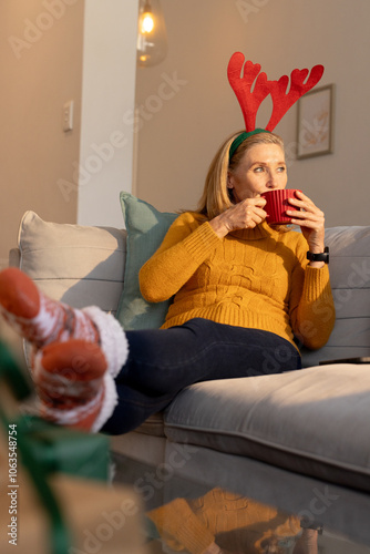 Christmas time, Relaxing at home, senior woman wearing reindeer headband sipping hot drink