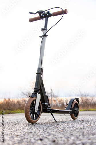 A scooter stands on the asphalt during sunset. Vertical photo.