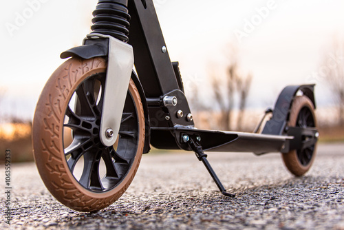 A scooter stands on the asphalt during sunset.