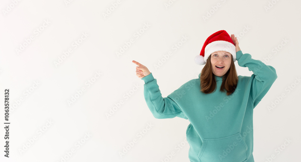 Excited young Santa woman in Christmas hat pointing index finger aside on mock up copy space put hand on head isolated on white background. Happy New Year holiday concept Excited young Santa woman in Christmas hat pointing index finger aside on mock up copy space put hand on head isolated on white background. Happy New Year holiday concept