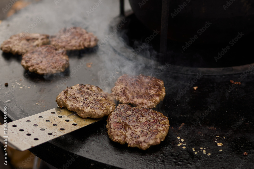 Sizzling, Mouthwatering Burgers Cooking Perfectly on a Griddle at a Summer BBQ Event Sizzling, Mouthwatering Burgers Cooking Perfectly on a Griddle at a Summer BBQ Event