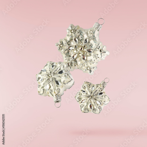 Christmas holliday image, Christmas bauble in shape of a snowlfake falling in the air isolated on pink background photo