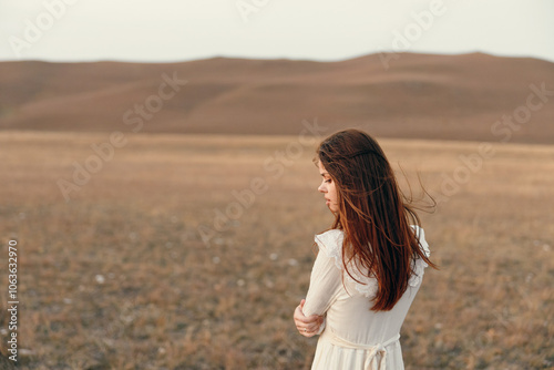 Woman in white dress standing in open field with mountain landscape in background serene travel beauty in nature concept