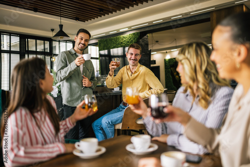 Fényképezés Group of female friends drinking coffee at the restaurant while the guys in the back try to flirt and send them drinks