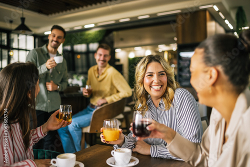 Vászonkép Group of female friends drinking coffee at the restaurant while the guys in the back try to flirt and send them drinks