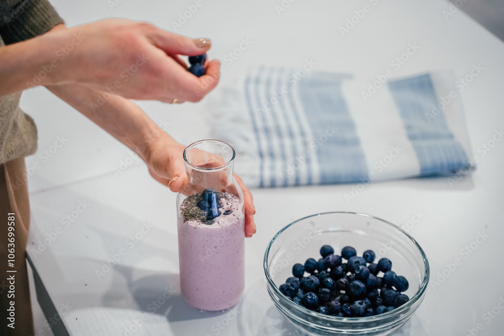 Close up of a woman making a smoothie with fruits and berries; selective focus. Healthy food concept.