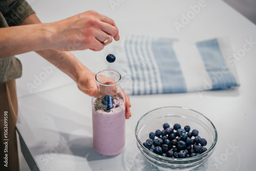 Close up of a woman making a smoothie with fruits and berries; selective focus. Healthy food concept.