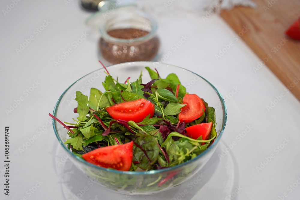 Full bowl of fresh green salad close up on a light table on a kitchen. Concept helpful and healthy food