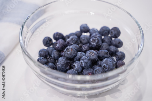 Fresh blueberries in glass bowl on white background