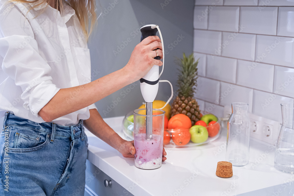 Close up of a woman making a smoothie with fruits and berries; selective focus. Healthy food concept.