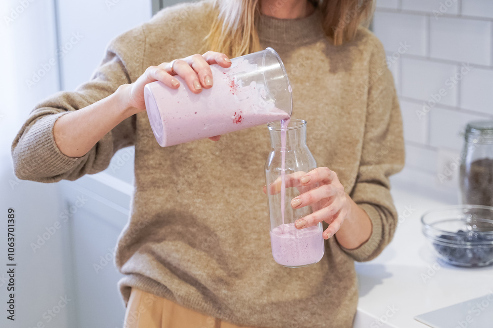 Close up of a woman making a smoothie with fruits and berries; selective focus. Healthy food concept.
