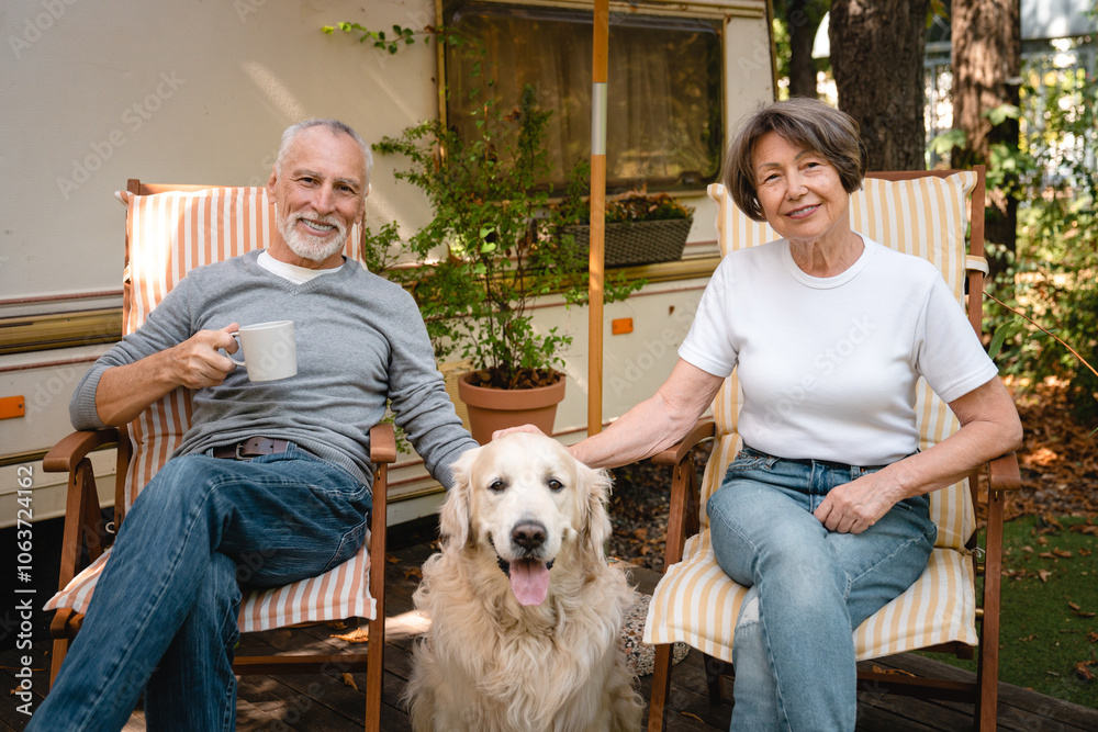 Happy couple relaxing on the yard of trailer camper van motor home together with dog Happy couple relaxing on the yard of trailer camper van motor home together with dog